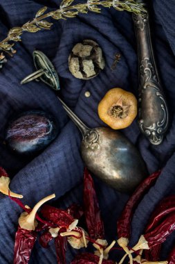 Gümüş kaşıkla, kurutulmuş meyvelerle, sebzelerle ve lacivert dokulu otlarla dolu bir hayat. Farklı nesnelerin üst görünüm fotoğrafı. Sonbaharın renkleri.