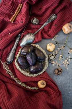 Kırmızı desenli pamuklu arka planda erik ve kurutulmuş bitkilerle dolu bir hayat. Farklı nesnelerin üst görünüm fotoğrafı. Sonbaharın renkleri. 