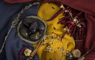 Erikler, kurutulmuş otlar, çiçekler ve sebzelerle dolu sakin bir hayat. Mavi, sarı ve kırmızı desenli kumaş arka plan. Sonbaharın renkleri. 