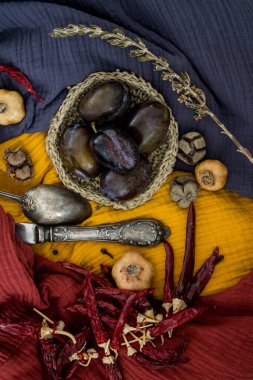 Erikler, kurutulmuş otlar, çiçekler ve sebzelerle dolu sakin bir hayat. Mavi, sarı ve kırmızı desenli kumaş arka plan. Sonbaharın renkleri. 