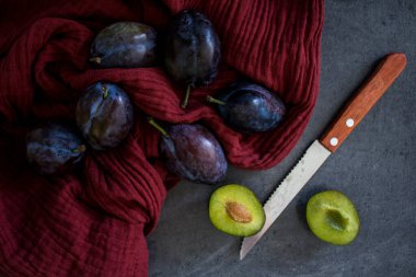 Kırmızı desenli arka planda taze erikler. Mutfak masasının en üstteki görüntüsü. Sonbahar ruh hali resmi. 