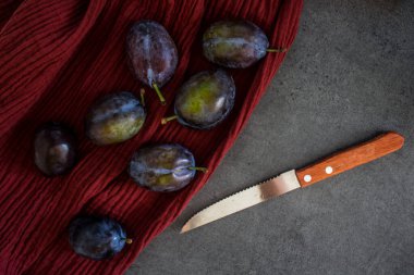 Kırmızı desenli arka planda taze erikler. Mutfak masasının en üstteki görüntüsü. Sonbahar ruh hali resmi. 