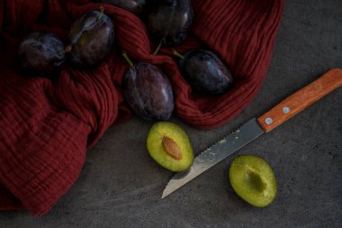 Kırmızı desenli arka planda taze erikler. Mutfak masasının en üstteki görüntüsü. Sonbahar ruh hali resmi. 