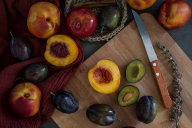 Masadaki güzel taze meyvelerin en üst görüntüsü. Kırmızı ve mavi desenli arka plan. Sulu erik ve nektarin renkleri. 