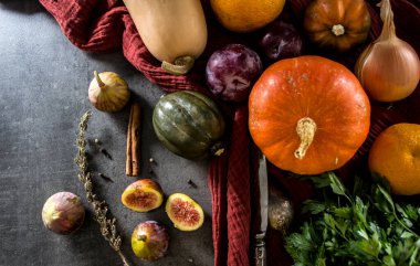 Gri masada taze sebzeler. Tereyağı, ceviz kabağı, balkabağı, altın külçe, havuç, incir, tatlı patates, soğan, portakal ve maydanoz. Sonbahar hasadı. Sağlıklı yeme kavramı.