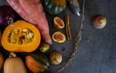 Gri masada taze sebzeler. Tereyağı, ceviz kabağı, balkabağı, altın külçe, havuç, incir, tatlı patates, soğan, portakal ve maydanoz. Sonbahar hasadı. Sağlıklı yeme kavramı.