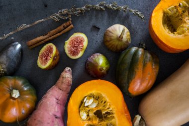 Gri masada taze sebzeler. Tereyağı, ceviz kabağı, balkabağı, altın külçe, havuç, incir, tatlı patates, soğan, portakal ve maydanoz. Sonbahar hasadı. Sağlıklı yeme kavramı.