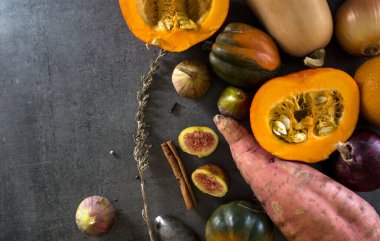 Sonbahar hasadı. Gri masada taze sebzeler. Palamut kabağı, altın külçe, havuç, incir, portakal. Sağlıklı yeme kavramı.