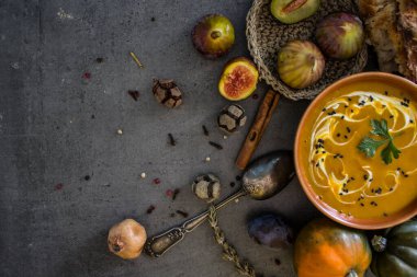 Gri masada taze ekmek ve gümüş kaşıkla balkabağı çorbası. Sonbahar makbuzları. Vejetaryen yemeğinin en iyi görüntüsü. Sağlıklı yeme kavramı. 