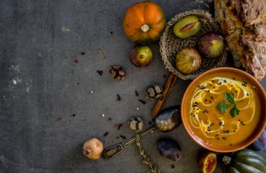 Gri masada taze ekmek ve gümüş kaşıkla balkabağı çorbası. Vejetaryen yemeğinin en iyi görüntüsü. Sağlıklı beslenme konsepti. Kopya alanı ile koyu desenli arkaplan. 