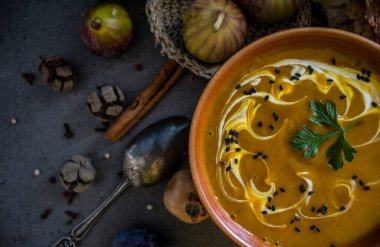Gri masada taze ekmek ve gümüş kaşıkla balkabağı çorbası. Sonbahar makbuzları. Vejetaryen yemeğinin en iyi görüntüsü. Sağlıklı yeme kavramı. 