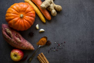 Gri desenli arka planda taze sonbahar sebzeleri ve fotokopi alanı. Kabak, havuç, tatlı patates ve baharat manzaralı bir fotoğraf. Sonbahar hasadı. Sağlıklı yeme kavramı. 