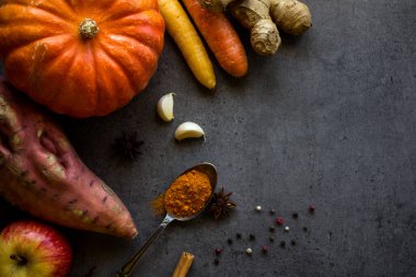 Gri desenli arka planda taze sonbahar sebzeleri ve fotokopi alanı. Kabak, havuç, tatlı patates ve baharat manzaralı bir fotoğraf. Sonbahar hasadı. Sağlıklı yeme kavramı. 
