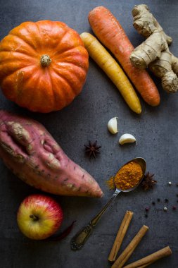 Gri desenli arka planda taze sonbahar sebzeleri ve fotokopi alanı. Kabak, havuç, tatlı patates ve baharat manzaralı bir fotoğraf. Sonbahar hasadı. Sağlıklı yeme kavramı. 