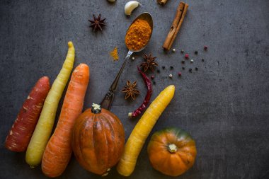 Gri desenli arka planda taze sonbahar sebzeleri ve fotokopi alanı. Kabak, havuç, tatlı patates ve baharat manzaralı bir fotoğraf. Sonbahar hasadı. Sağlıklı yeme kavramı. 