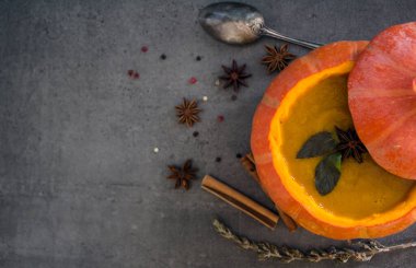 Kabak kabağında kabak çorbası. Balkabağı, elma, havuç, anason yıldızları ve tarçın çubuklarının en iyi görüntü fotoğrafı. Gri arkaplan.