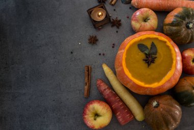 Kabak kabağında kabak çorbası. Arka planda gri dokuma ve fotokopi alanı. Anasonlu, biberiyeli, tarçınlı ve gümüş kaşıklı sonbahar yemeklerinin en iyi görüntüsü..