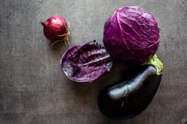 Kırmızı lahana, patlıcan ve soğan gri masada.. 