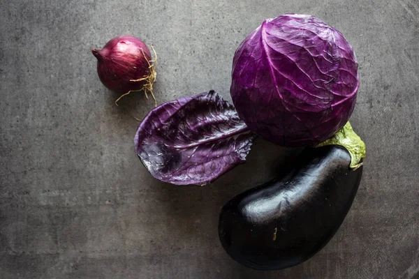 Kırmızı lahana, patlıcan ve soğan gri masada.. 