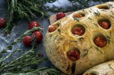Gri desenli arka planda biberiye ve kiraz domatesli ev yapımı Focaccia ekmeği. Üst görüntü fotoğrafı. Geleneksel aşçılık konsepti.