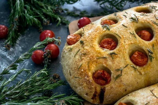 Gri desenli arka planda biberiye ve kiraz domatesli ev yapımı Focaccia ekmeği. Üst görüntü fotoğrafı. Geleneksel aşçılık konsepti.
