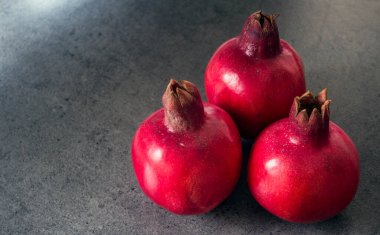 Koyu gri arkaplanda üç nar ve fotokopi alanı. Kırmızı meyveli fotoğraf. Yahudi Yeni Yılı Sembolleri.  