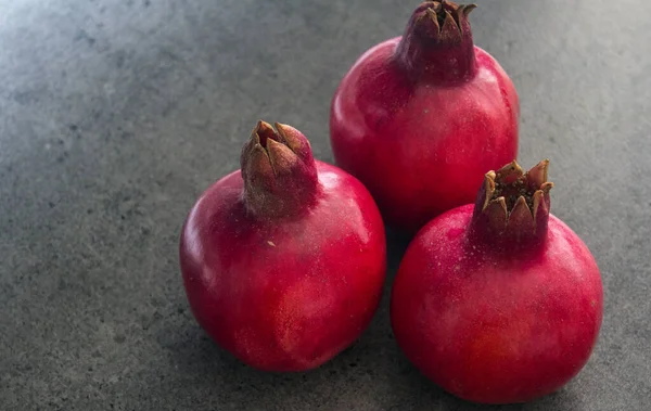 Koyu gri arkaplanda üç nar ve fotokopi alanı. Kırmızı meyveli fotoğraf. Yahudi Yeni Yılı Sembolleri.  