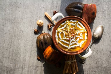 Seramik kapta baharatlı kabak çorbası. Cadılar Bayramı akşam yemeği manzaralı fotoğraf. Kopyalama alanı olan koyu gri arkaplan.