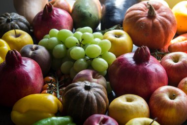 Masada taze sonbahar meyveleri ve sebzeleri. Narlar, üzümler, kabaklar, elmalar ve havuçlar.. 