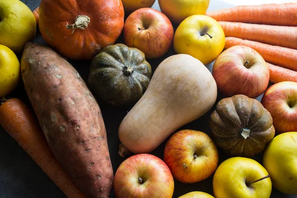 Sonbahar hasadı. Gri masada taze sebzeler. Tereyağı, ceviz kabağı, balkabağı, altın külçe, havuç, tatlı patates, elma. Sağlıklı yeme kavramı.