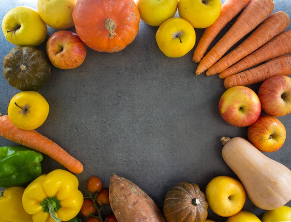 Kabakların, havuçların, elmaların, vişneli domateslerin ve üzümlerin gri arka planda fotokopi alanındaki en iyi fotoğrafı. Taze sonbahar sebzelerinden yapılmış renkli çerçeve veya sınır. 
