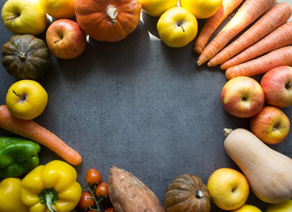 Kabakların, havuçların, elmaların, vişneli domateslerin ve üzümlerin gri arka planda fotokopi alanındaki en iyi fotoğrafı. Taze sonbahar sebzelerinden yapılmış renkli çerçeve veya sınır. 
