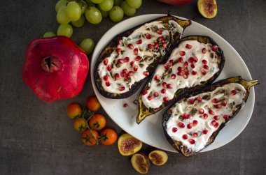 Yoğurt soslu ızgara patlıcan ve gri masada nar tohumları. Yeni yapılmış vejetaryen yemeğinin en iyi görüntüsü.. 