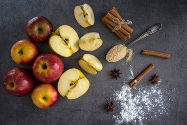 Elmalı turta malzemesi, en iyi görüntü fotoğrafı. Kırmızı elmalar, yumurtalar, tarçın çubuklar, tereyağı ve kahverengi şeker bir masada.