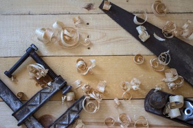 Marangoz aletleri fotoğrafı kapatır. Klasik el testeresi, kıskaç, uçak aracı ve ahşap talaş üst görünüm. 