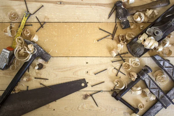 Old plane tool close up photo. Wooden background with copy space. Carpenter work place. Carpenter tools on wooden planks of different types. Home renovating concept. Clump, hammer, plane tool and nails close up photo.