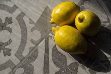 Mutfak masasında üç limon. Taze sarı meyvelerin en üstteki fotoğrafı. Kopyalama alanı olan gri arkaplan. 