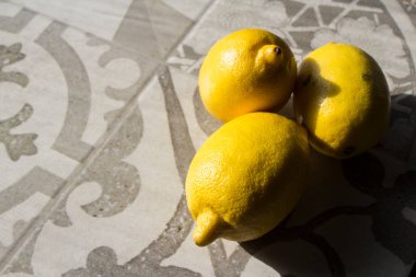 Mutfak masasında üç limon. Taze sarı meyvelerin en üstteki fotoğrafı. Kopyalama alanı olan gri arkaplan. 