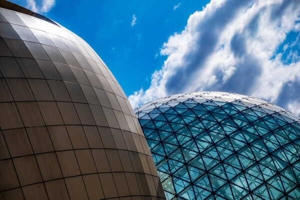 Modern stylish office building. Rounded geometrical shapes with golden checkered pattern. Glass dome with triangular glazing and black metal frames. Unique design elements. 