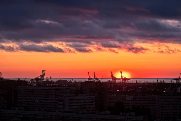 Limanda ve endüstriyel vinçlerde yumuşak turuncu gün batımında güzel bir manzara. Deniz kenarı ile modern şehir manzarasının aksine güzel bir doğa..