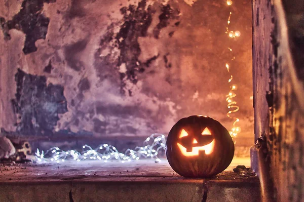 Cadılar Bayramı balkabağı, arka planda koyu bir arka plan ve arka tarafta bokeh ışıkları olan bir merdivende parlıyor..