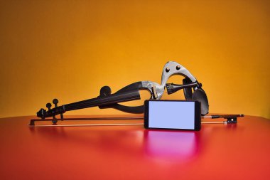 Elektrikli kemanın altında kırmızı arka planda, arkasında sarı arka planda. Evde ders vermek için cep telefonu puanıyla..