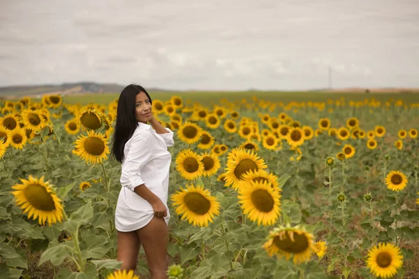 Genç, çekici, Latin esmer, üzerinde kılıçlar olan beyaz bir gömlek giyen, çapkın ve eğlenceli, ayçiçeği tarlasının ortasında duran bir kadın. Kavram: doğa, tarım, kırsal.