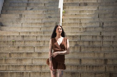 Genç bir kadın, esmer, uzun boylu, zayıf ve çok dövmeli, kahverengi bir elbise giyiyor, sonsuzluğa bakıyor, tatlı, masum ve yalnız, merdivenlerde duruyor. Gençlik kavramı, bin yıllık.