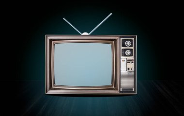 Masanın önünde eski bir televizyon alıcısı ve anten. Gradyan yeşil duvar arkaplanı, perspektif üzerinde kesilmiş ekran, ahşap zemin, mavi parıltı ve koyu renk ton.