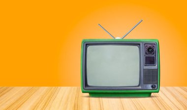 yeşil retro eski televizyon alıcısı masa önünde gradyan turuncu duvar arkaplanı, perspektif ahşap zemin dokusu ve klasik televizyon