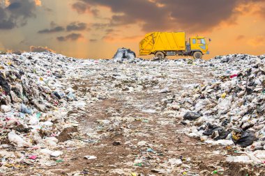 Çöp yığını çöplüğe ya da çöplüğe, kamyon belediye, çöp yığını ve gün batımı ya da gündoğumu geçmişine, kirlilik kavramına atılıyor