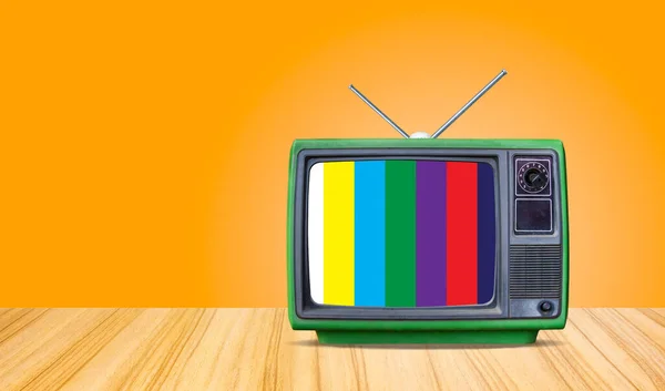 green retro old television receiver and test screen on table front gradient orange  wall background,perspective wooden floor texture and,vintage tv