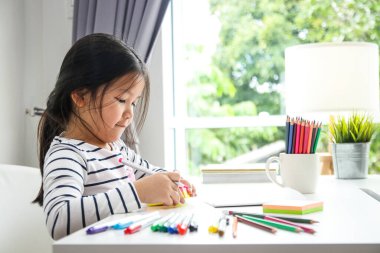 Asyalı kızlar evde ders çalışıyor. Çizim masasına oturdu. COVID-19 virüsünün yayılmasını azaltmak için sosyal mesafeleme kavramı