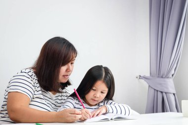Anneler küçük kızlarına ev ödevi öğretirler. Koronavirüsün yayılmasını azaltmak için sosyal mesafe kavramı (COVID-19). Boşluğu kopyala